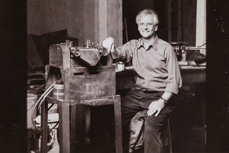 Robert Gamblin in his rearly years sitting at the paint mill, making his colors.